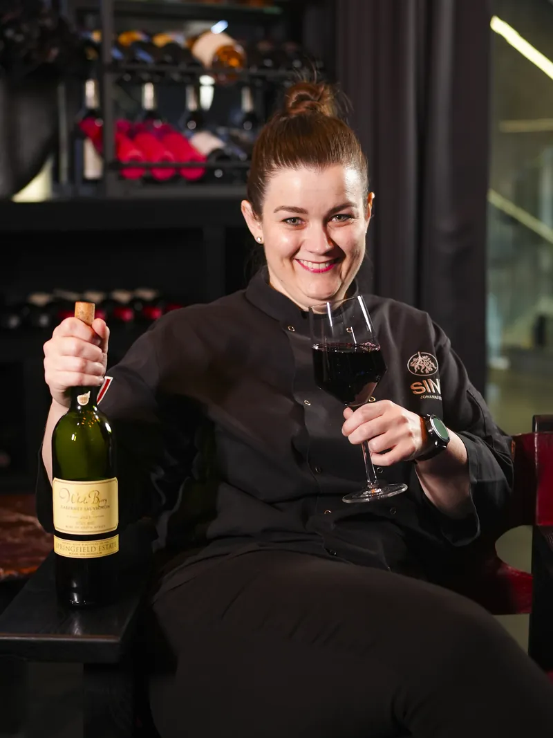 A SINN team member with a bottle and a glass of red wine